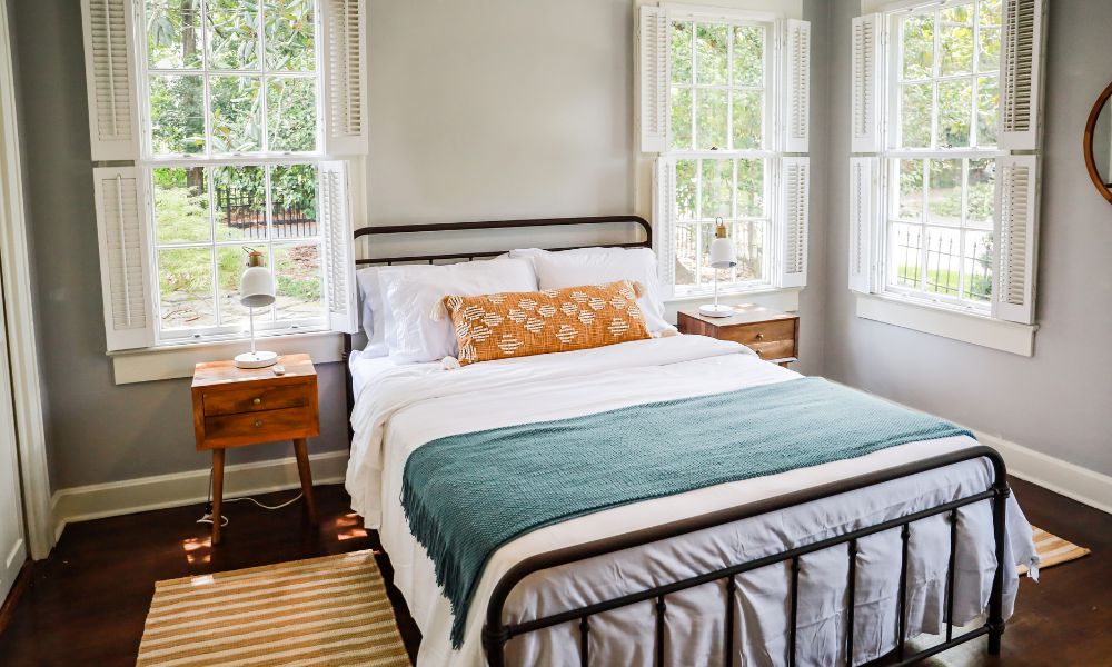 A small bedroom and neat bed and a night stand