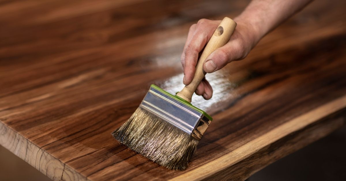 Two young ladies talking one holding a book another with box in a collge dorm