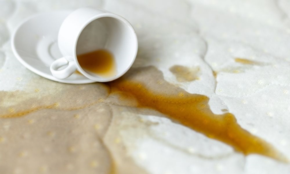 A tea cup fell and spilled the tea on the bed